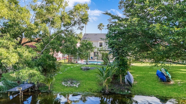 view of property's community with a pool, a water view, a yard, and a dock