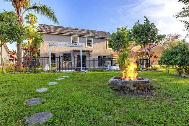 back of house with an outdoor fire pit, a yard, and a pergola