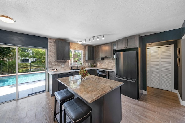 kitchen with sink, decorative backsplash, a center island, dark brown cabinetry, and black appliances