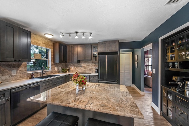 kitchen featuring sink, dishwasher, dark brown cabinets, fridge, and a center island