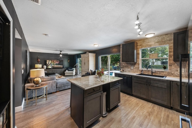 kitchen featuring dark brown cabinetry, sink, a center island, light hardwood / wood-style flooring, and black dishwasher