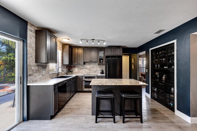 kitchen featuring plenty of natural light, sink, dark brown cabinetry, and black appliances