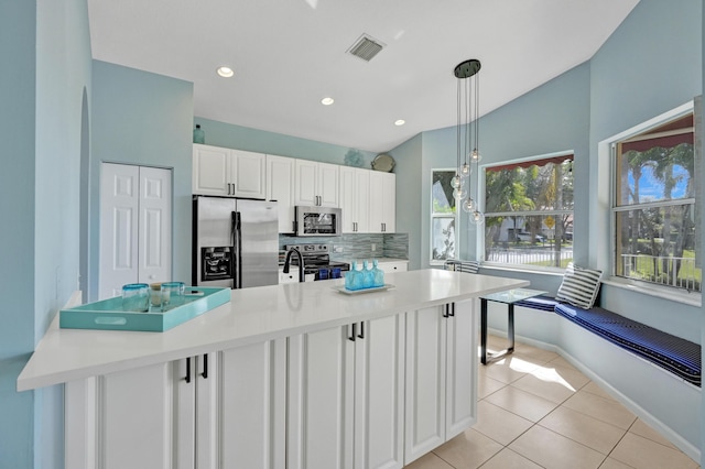 kitchen with pendant lighting, light tile patterned floors, appliances with stainless steel finishes, white cabinetry, and decorative backsplash