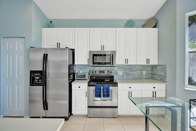 kitchen featuring white cabinetry, appliances with stainless steel finishes, light tile patterned floors, and backsplash