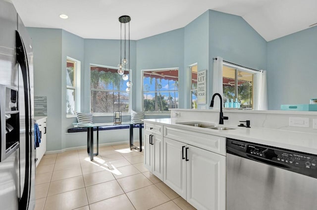 kitchen with lofted ceiling, sink, hanging light fixtures, stainless steel appliances, and white cabinets