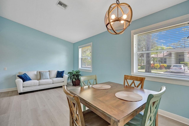 dining area featuring vaulted ceiling, a notable chandelier, and light hardwood / wood-style flooring