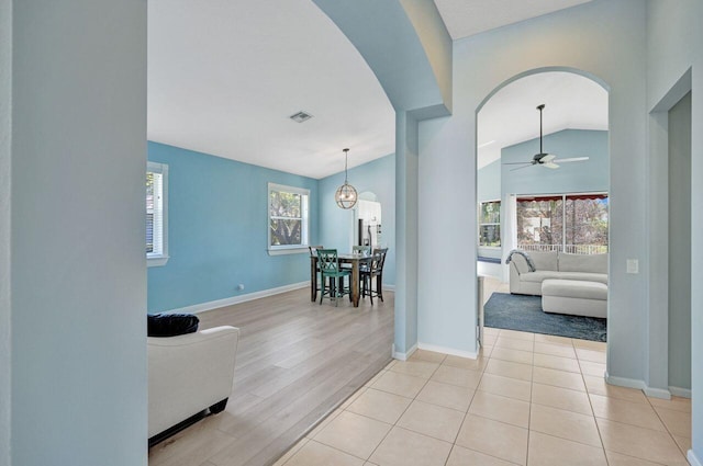 hallway with vaulted ceiling and light wood-type flooring