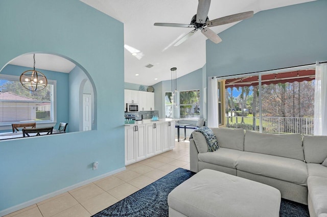 living room featuring high vaulted ceiling, plenty of natural light, ceiling fan with notable chandelier, and light tile patterned floors