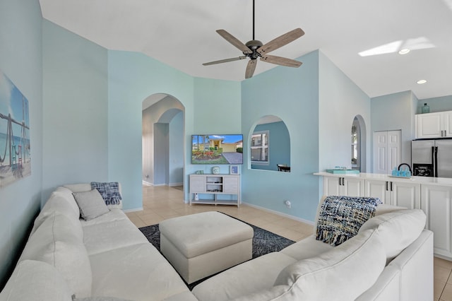 tiled living room with ceiling fan and high vaulted ceiling