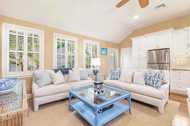 living room with ceiling fan, vaulted ceiling, and light hardwood / wood-style flooring