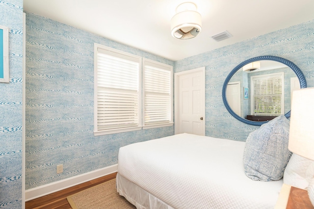 bedroom with multiple windows and dark wood-type flooring