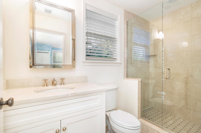 bathroom featuring vanity, toilet, and a shower with shower door