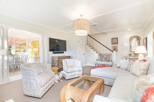 living room with a notable chandelier, crown molding, built in features, and decorative columns