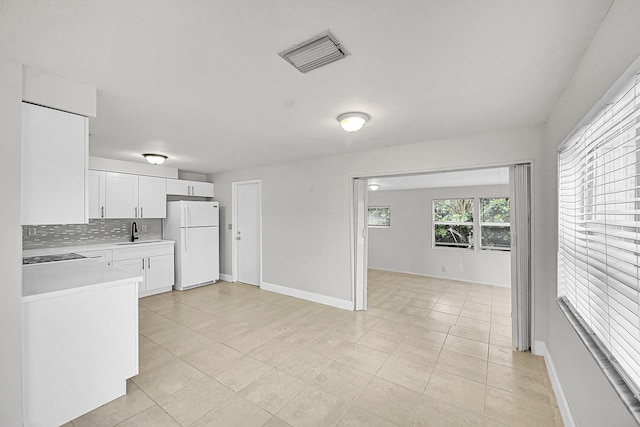 kitchen featuring light tile patterned flooring, sink, white cabinets, backsplash, and white fridge