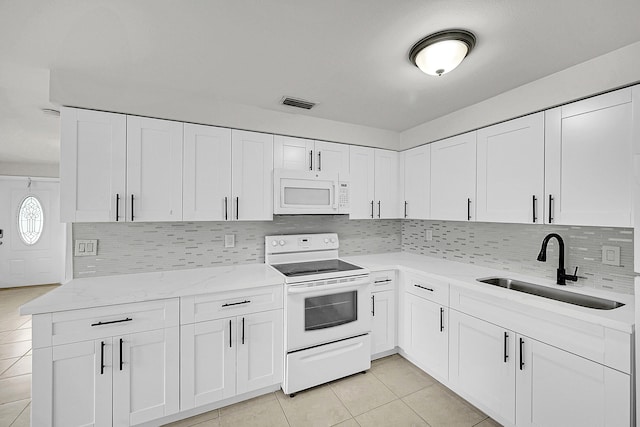 kitchen featuring white cabinetry, sink, backsplash, light tile patterned floors, and white appliances