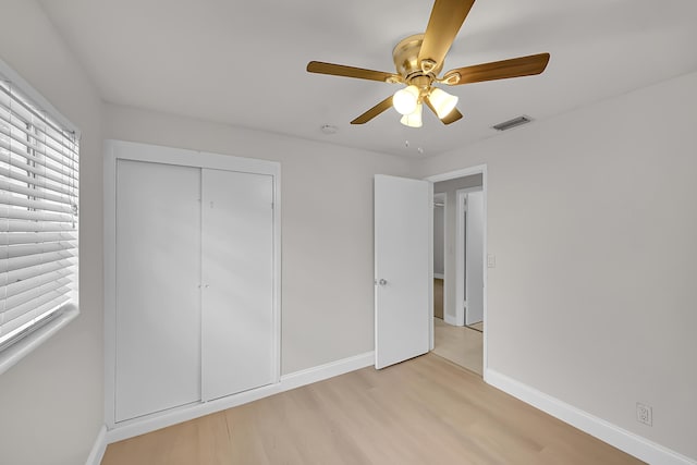 unfurnished bedroom featuring ceiling fan, a closet, and light wood-type flooring