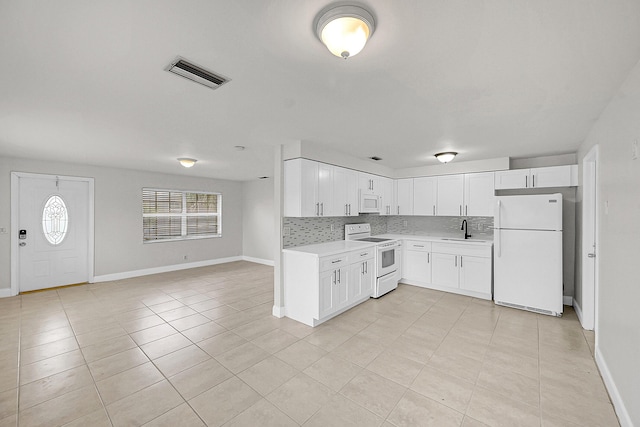 kitchen featuring sink, white appliances, white cabinets, and backsplash