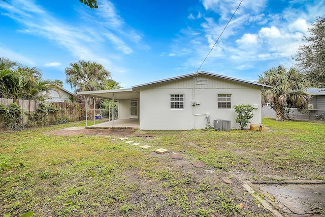 rear view of property featuring central AC unit, a lawn, and a patio