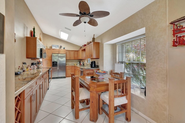 kitchen with stainless steel appliances, vaulted ceiling, light tile patterned floors, and light stone counters