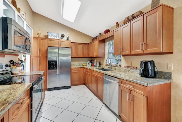 kitchen with lofted ceiling, sink, light tile patterned floors, appliances with stainless steel finishes, and light stone countertops