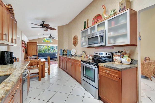 kitchen with light stone counters, vaulted ceiling, light tile patterned floors, appliances with stainless steel finishes, and ceiling fan