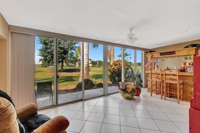 sunroom / solarium with indoor bar, a healthy amount of sunlight, and ceiling fan