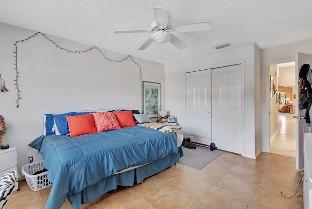 tiled bedroom featuring ceiling fan, a textured ceiling, and a closet