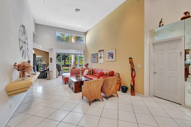 living room with a towering ceiling, a textured ceiling, and light tile patterned flooring