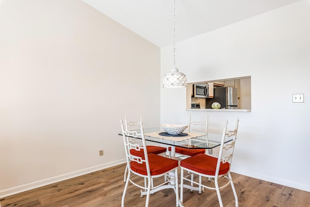 dining area featuring hardwood / wood-style flooring and vaulted ceiling