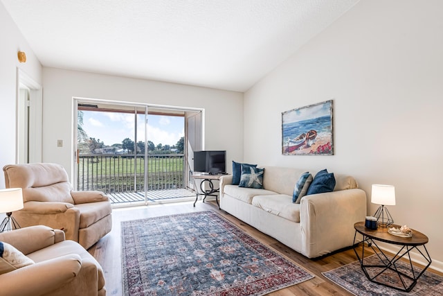 living room featuring hardwood / wood-style flooring, vaulted ceiling, and a textured ceiling