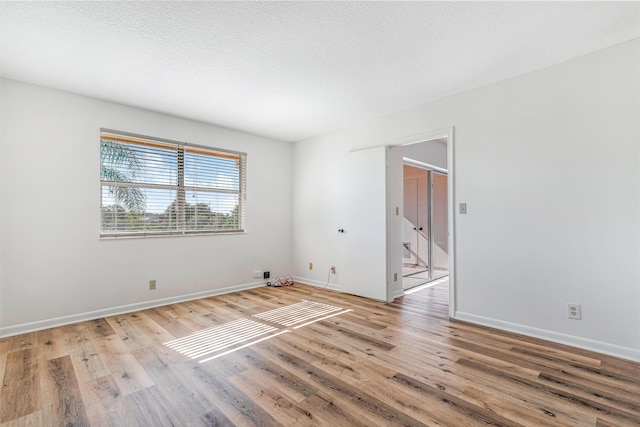 unfurnished room with light hardwood / wood-style floors and a textured ceiling