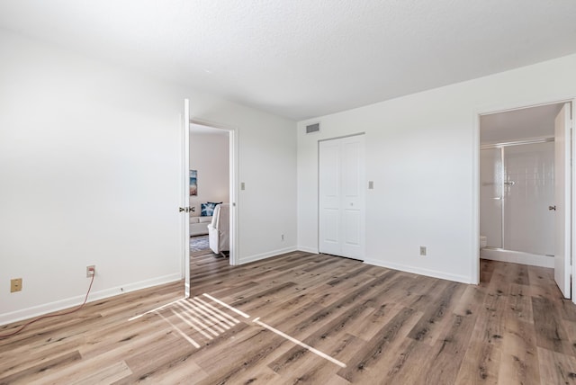 unfurnished bedroom featuring a closet, hardwood / wood-style floors, and a textured ceiling