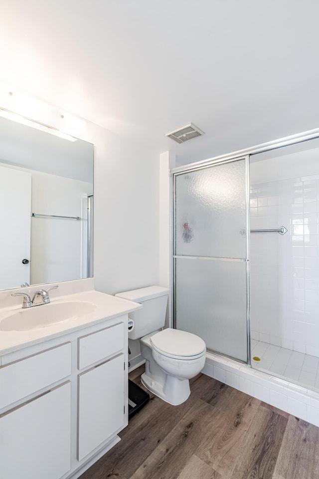 bathroom with wood-type flooring, toilet, vanity, and walk in shower