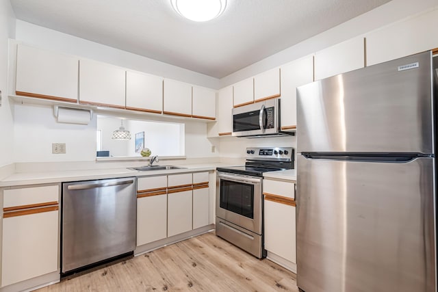 kitchen featuring white cabinetry, sink, light hardwood / wood-style flooring, and stainless steel appliances