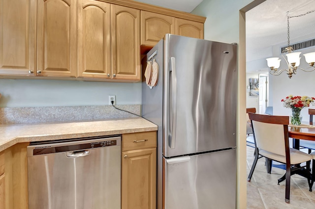 kitchen featuring light tile patterned floors, appliances with stainless steel finishes, hanging light fixtures, a notable chandelier, and light brown cabinets