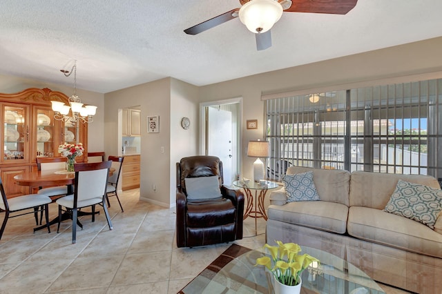 living room featuring light tile patterned floors, ceiling fan with notable chandelier, and a textured ceiling