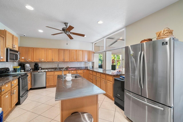 kitchen featuring sink, a center island with sink, light tile patterned floors, stainless steel appliances, and backsplash