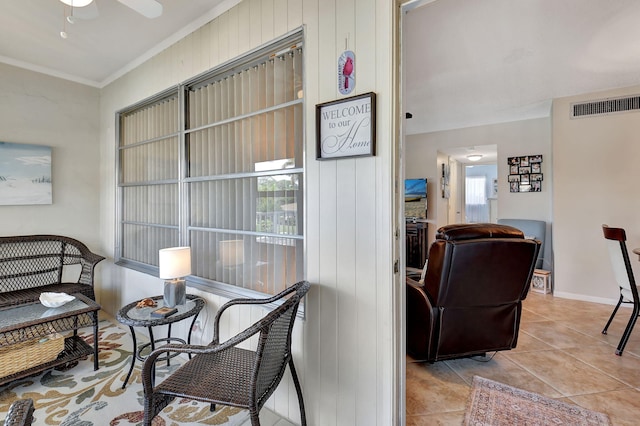 living area with light tile patterned flooring, ceiling fan, and crown molding