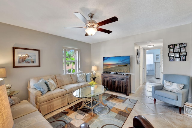 living room featuring ceiling fan, a textured ceiling, and light tile patterned floors