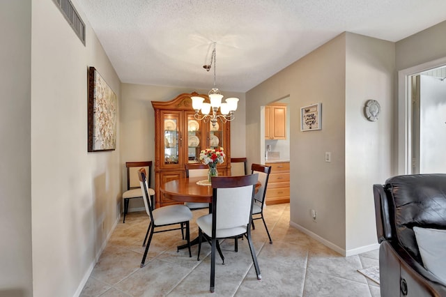 tiled dining space featuring an inviting chandelier and a textured ceiling