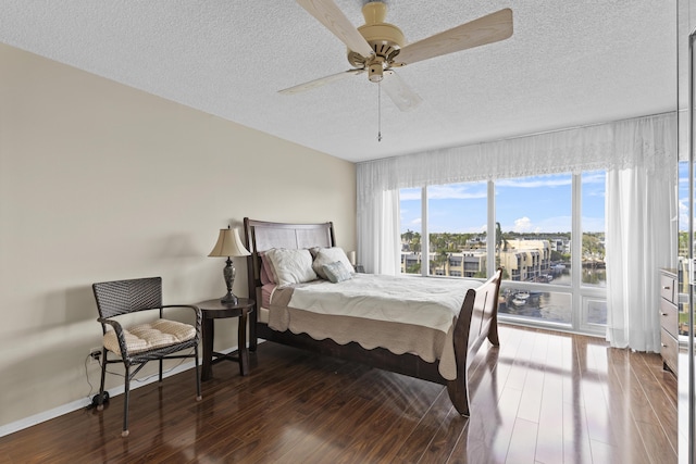 bedroom featuring dark hardwood / wood-style flooring, ceiling fan, and a textured ceiling