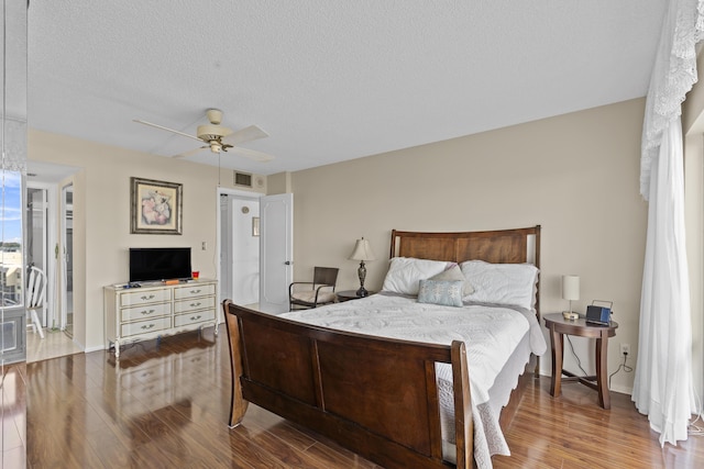 bedroom with ceiling fan, hardwood / wood-style floors, and a textured ceiling