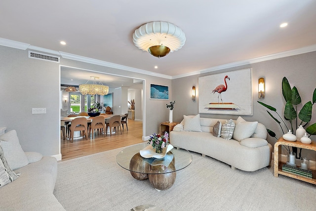 living room with hardwood / wood-style flooring, crown molding, and an inviting chandelier