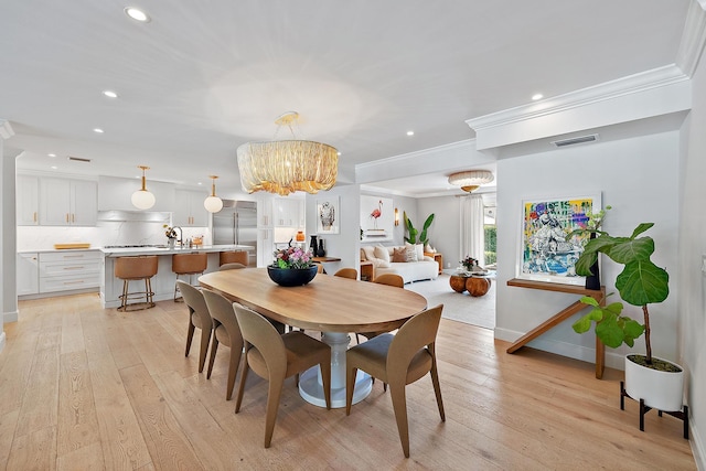 dining area with crown molding, light hardwood / wood-style floors, and a notable chandelier