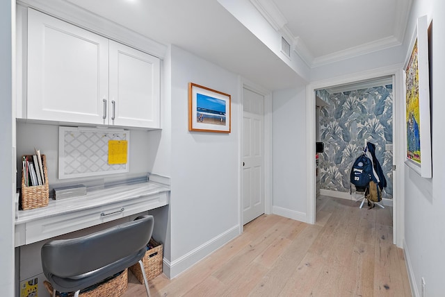 office space featuring light hardwood / wood-style flooring, built in desk, and ornamental molding