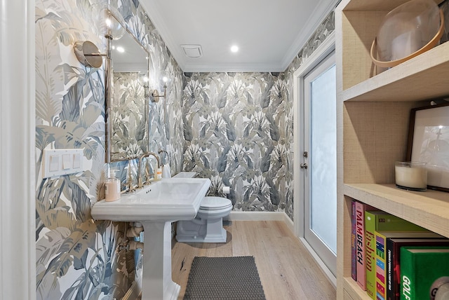 bathroom featuring hardwood / wood-style floors, ornamental molding, and toilet