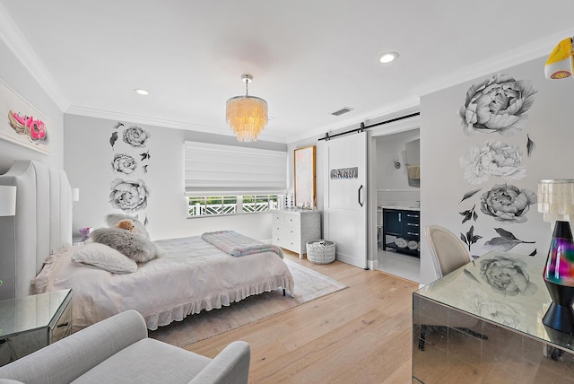 bedroom with connected bathroom, light hardwood / wood-style floors, ornamental molding, and a barn door