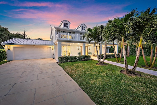 view of front of house featuring a balcony, a garage, and a lawn