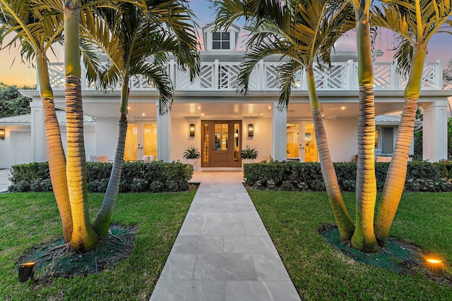 exterior entry at dusk featuring french doors and a lawn