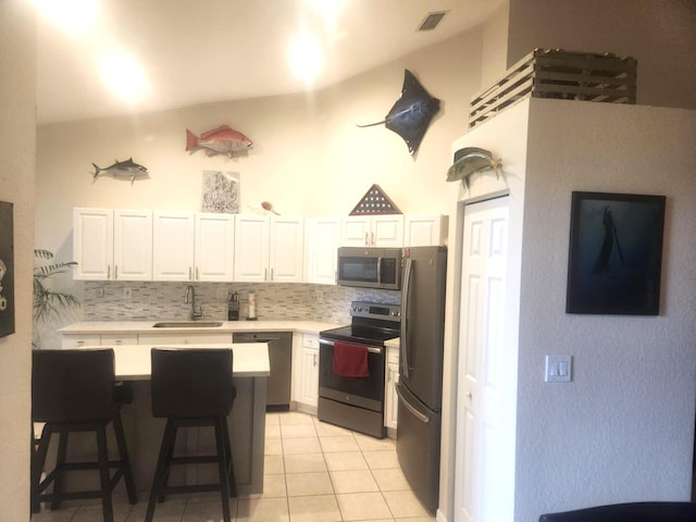 kitchen with sink, a breakfast bar area, stainless steel appliances, decorative backsplash, and white cabinets